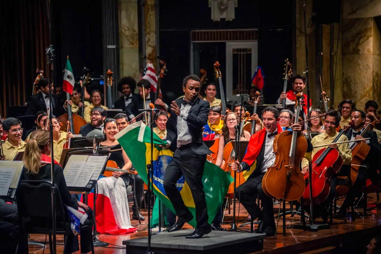 Orchestra of the Americas in concert, conductor mid-leap